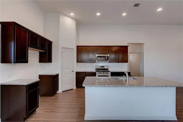 a living room with stainless steel appliances kitchen island granite countertop a stove a sink and a microwave