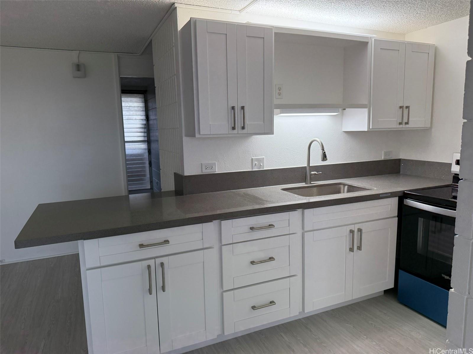 3215 Ala Ilima Street, Unit A1202 Honolulu, HI 96818 - Photo 19 of 20 a kitchen with granite countertop white cabinets and sink