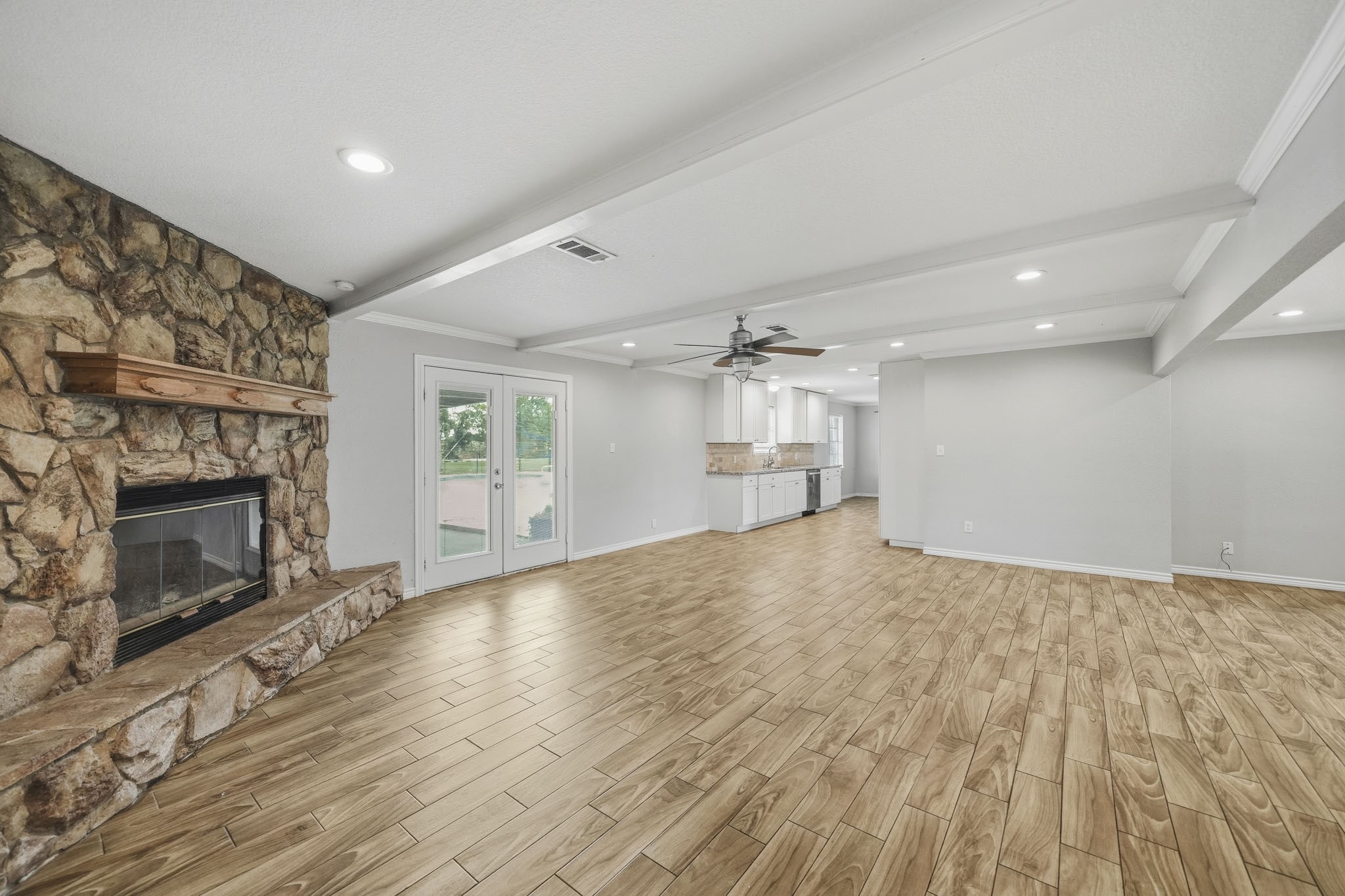 302 Country Road 893 Angleton, TX 77515 - Photo 12 of 26 This spacious living area features a cozy stone fireplace, wood-look flooring, and recessed lighting. It opens seamlessly to a bright kitchen with ample cabinetry, ideal for entertaining.