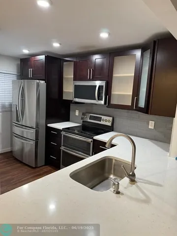 a kitchen with stainless steel appliances wooden cabinets a sink and a refrigerator