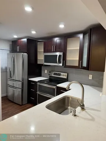 a kitchen with stainless steel appliances kitchen island granite countertop a refrigerator and a sink