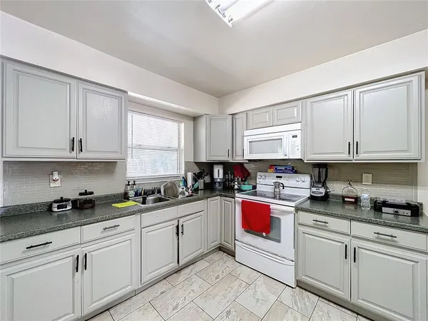 a kitchen with stainless steel appliances granite countertop white cabinets sink and window