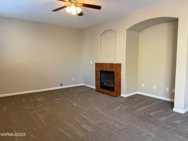 an empty room with a fireplace and chandelier fan