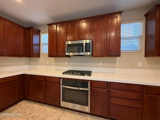 a kitchen with stainless steel appliances granite countertop wooden cabinets and a sink