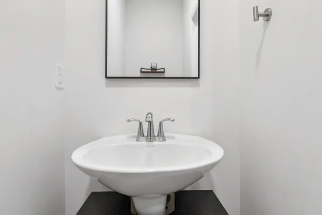 a white sink sitting under a bathroom mirror