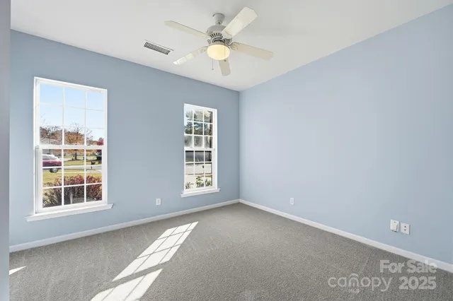 an empty room with windows and ceiling fan