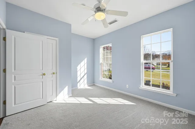 an empty room with windows and chandelier fan