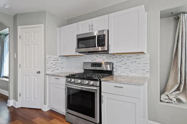 a kitchen with stainless steel appliances white cabinets a stove a microwave and a refrigerator