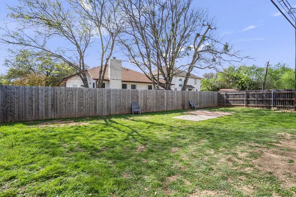 a view of a backyard with a large tree and wooden fence