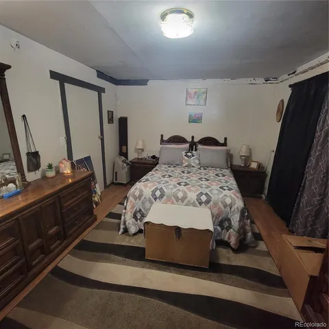 a bedroom with a bed a flat tv screen and a dresser