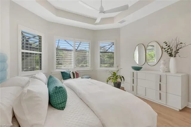 a spacious bedroom with a bed a mirror on dresser and a large window