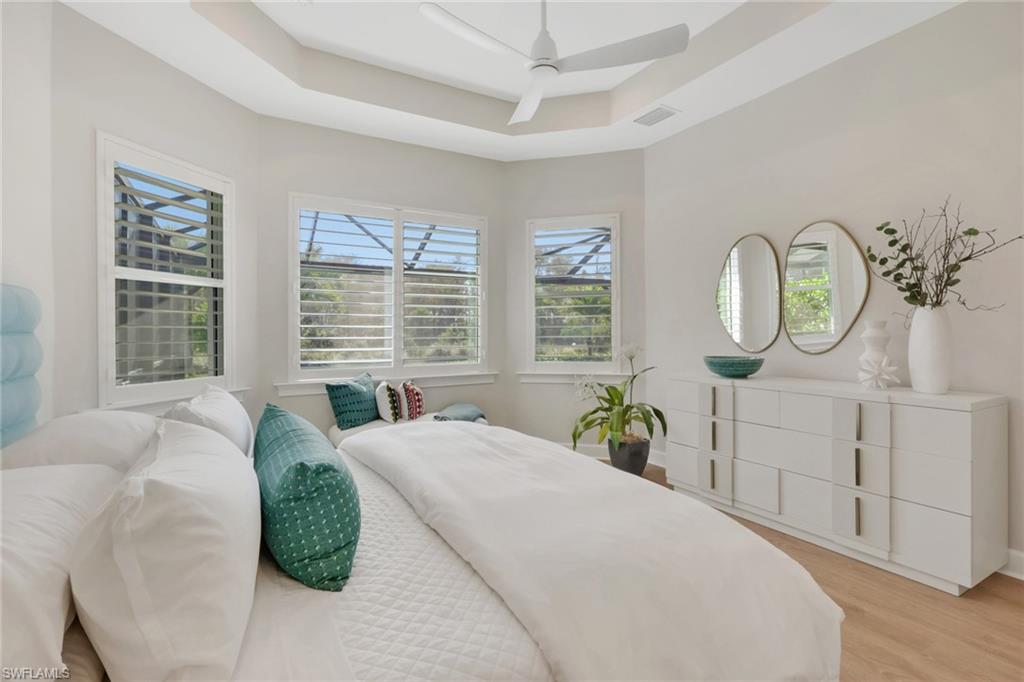 6253 Antigua Way Naples, FL 34113 - Photo 15 of 41 a spacious bedroom with a bed a mirror on dresser and a large window