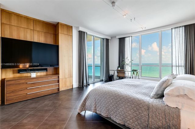 a bedroom with a bed and large windows