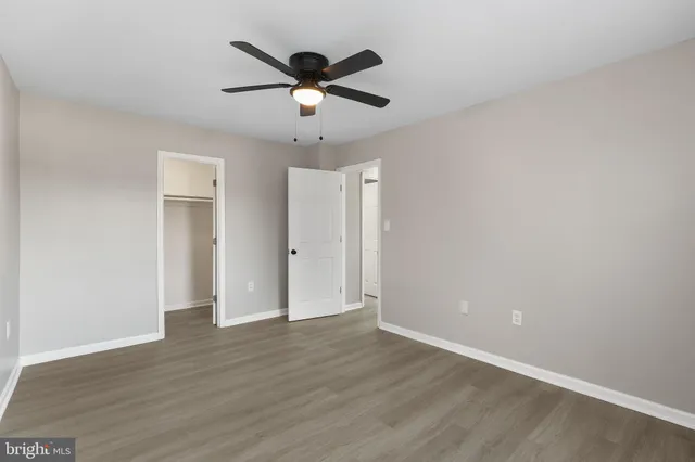an empty room with wooden floor and ceiling fan