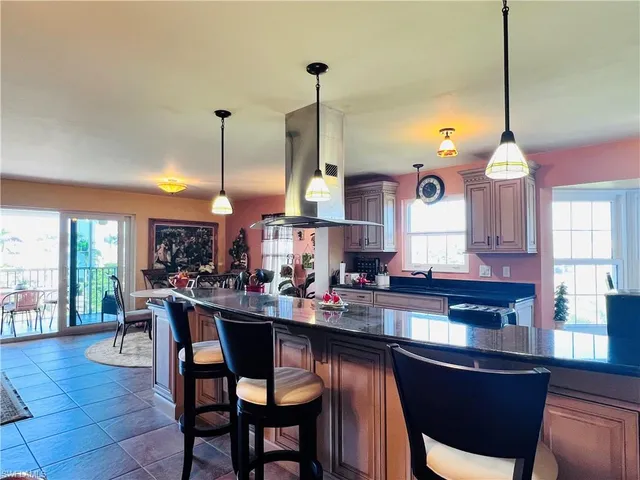 a living room with a potted plant and open kitchen view