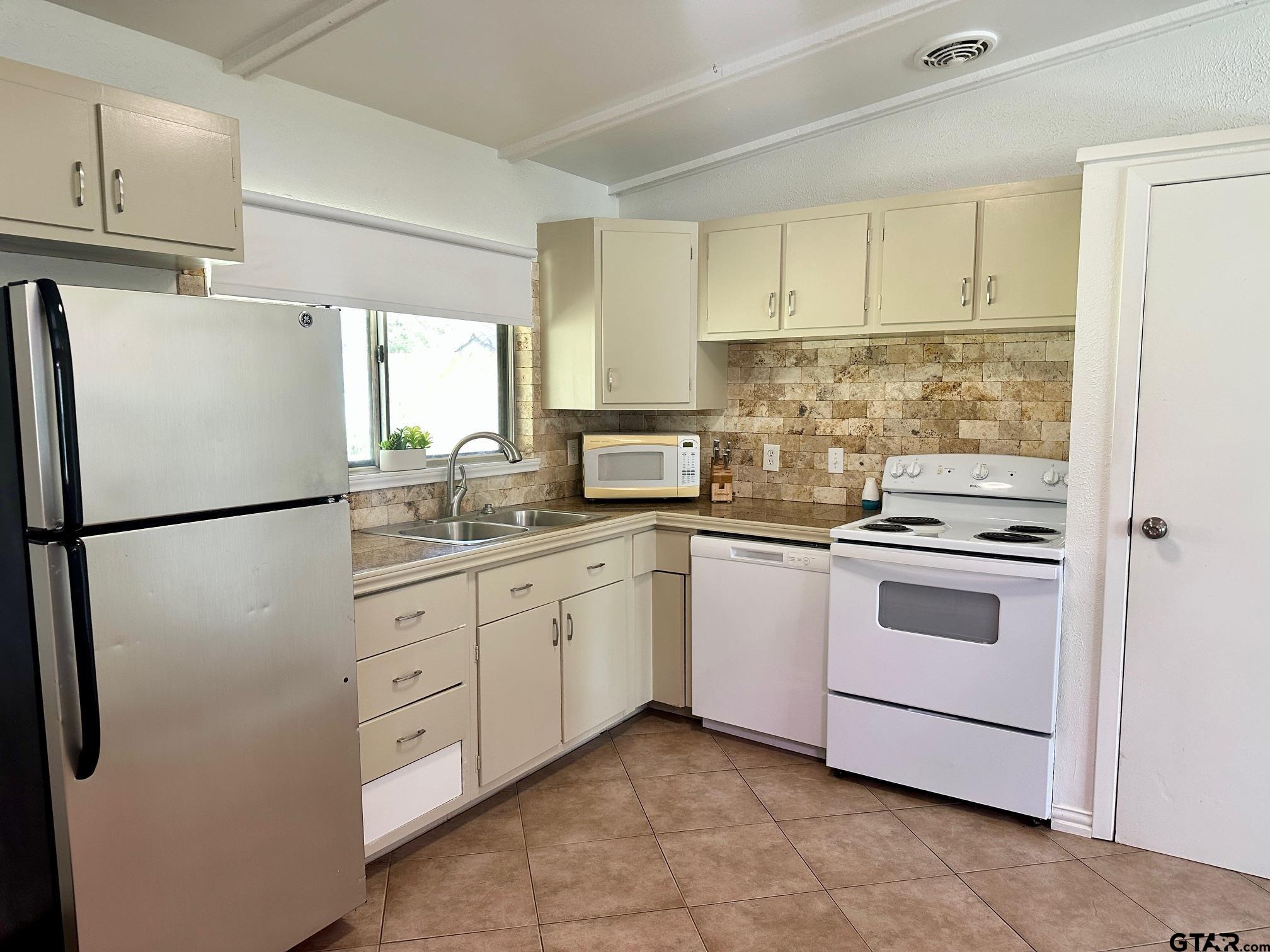 2412 East Devine Street Tyler, TX 75701 - Photo 9 of 27 a kitchen with white cabinets stainless steel appliances and a refrigerator