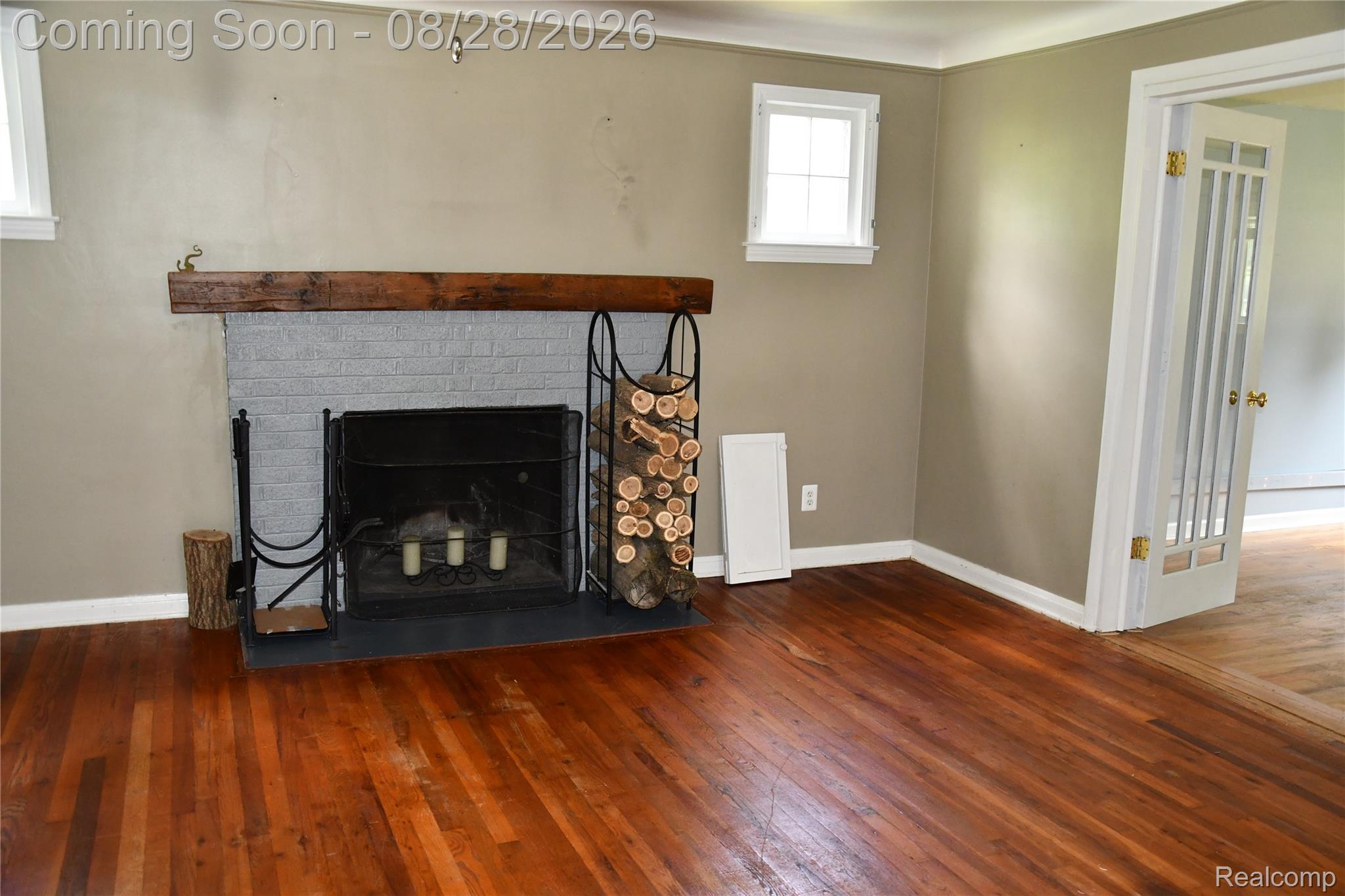 9039 Peer Road South Lyon, MI 48178 - Photo 26 of 47 Hardwood flooring, brick fireplace with wood mantel, white trim, and a paneled glass door