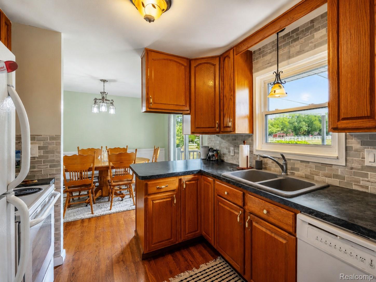 Kitchen featuring wood cabinetry, dark countertops, and a subway tile backsplash