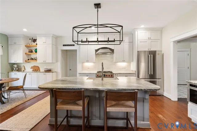 a kitchen with kitchen island a dining table chairs cabinets and stainless steel appliances