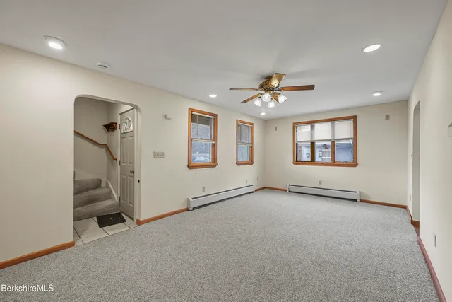 an empty room with windows and ceiling fan