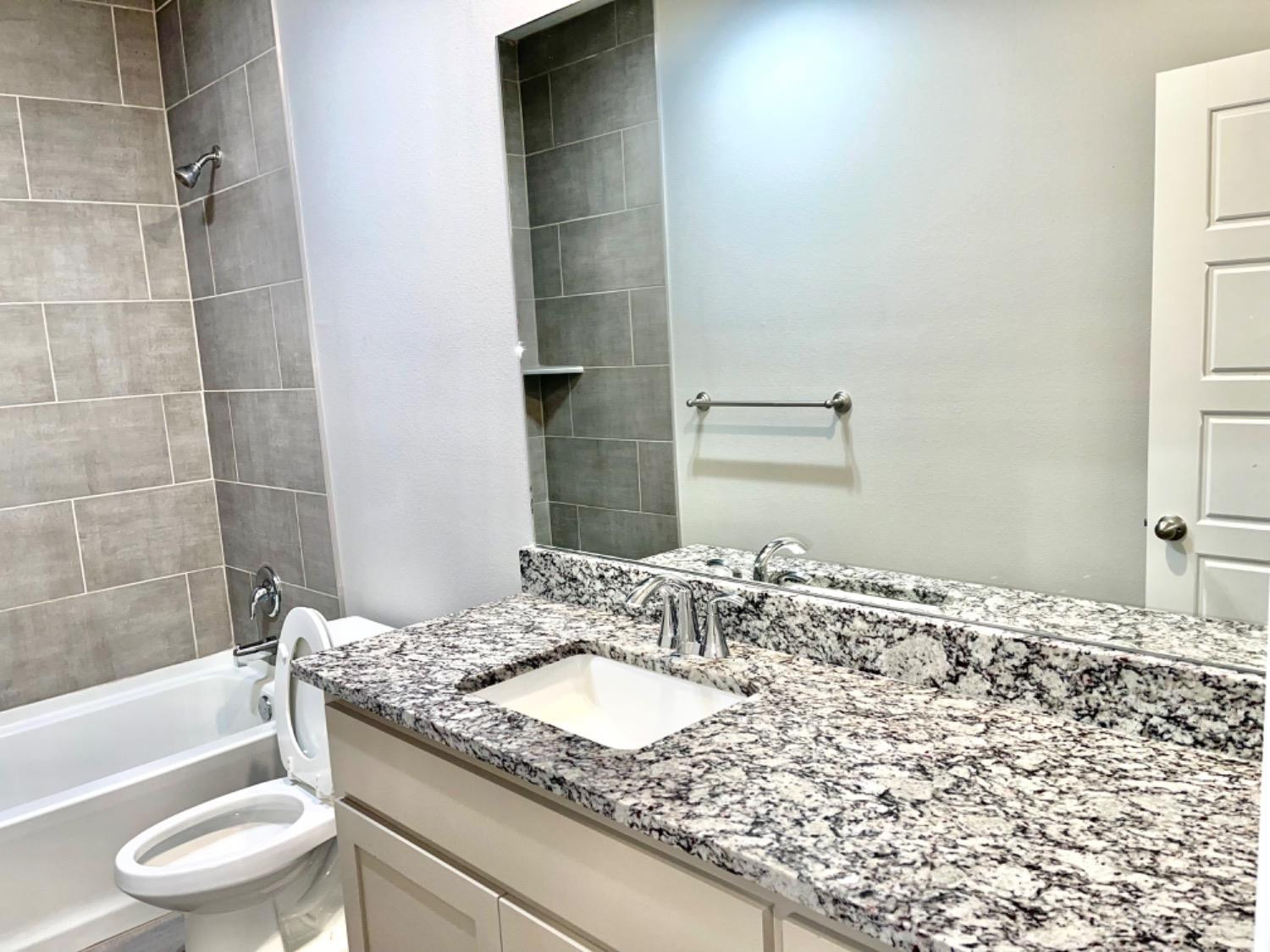 7729 96th Street Lubbock, TX 79424 - Photo 24 of 35 a bathroom with a granite countertop sink and a mirror