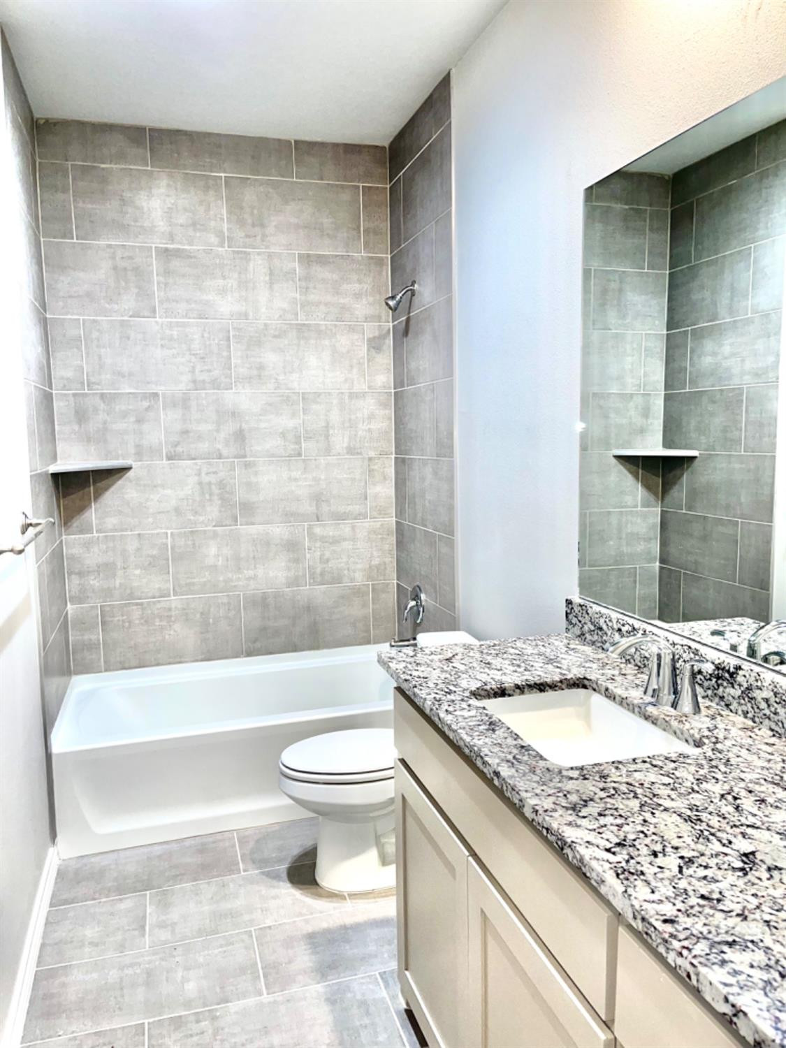 7729 96th Street Lubbock, TX 79424 - Photo 25 of 35 a bathroom with a granite countertop sink a toilet a mirror and bathtub