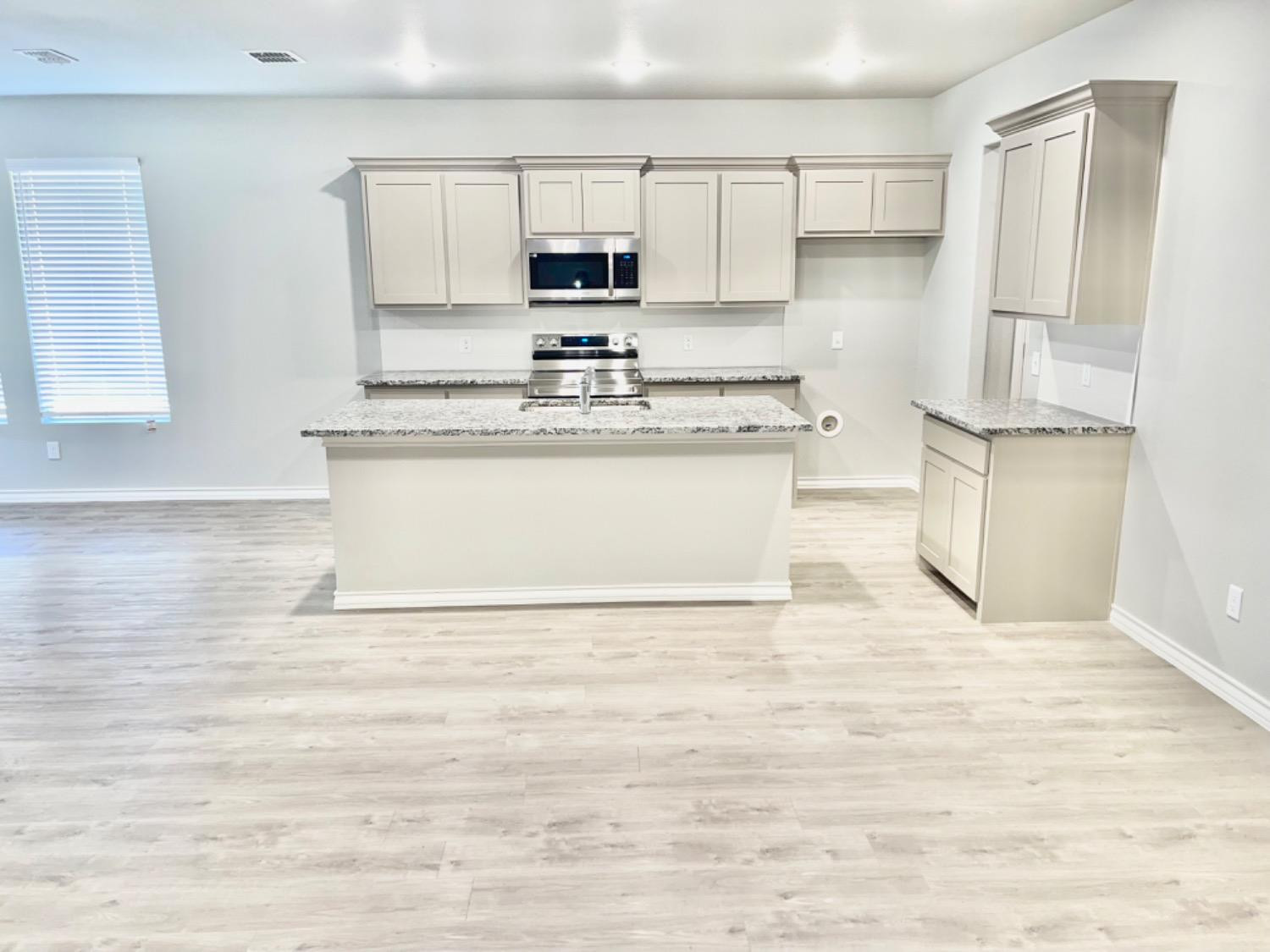 7729 96th Street Lubbock, TX 79424 - Photo 5 of 35 a view of kitchen with stainless steel appliances granite countertop a stove a sink a refrigerator and white cabinets with wooden floor