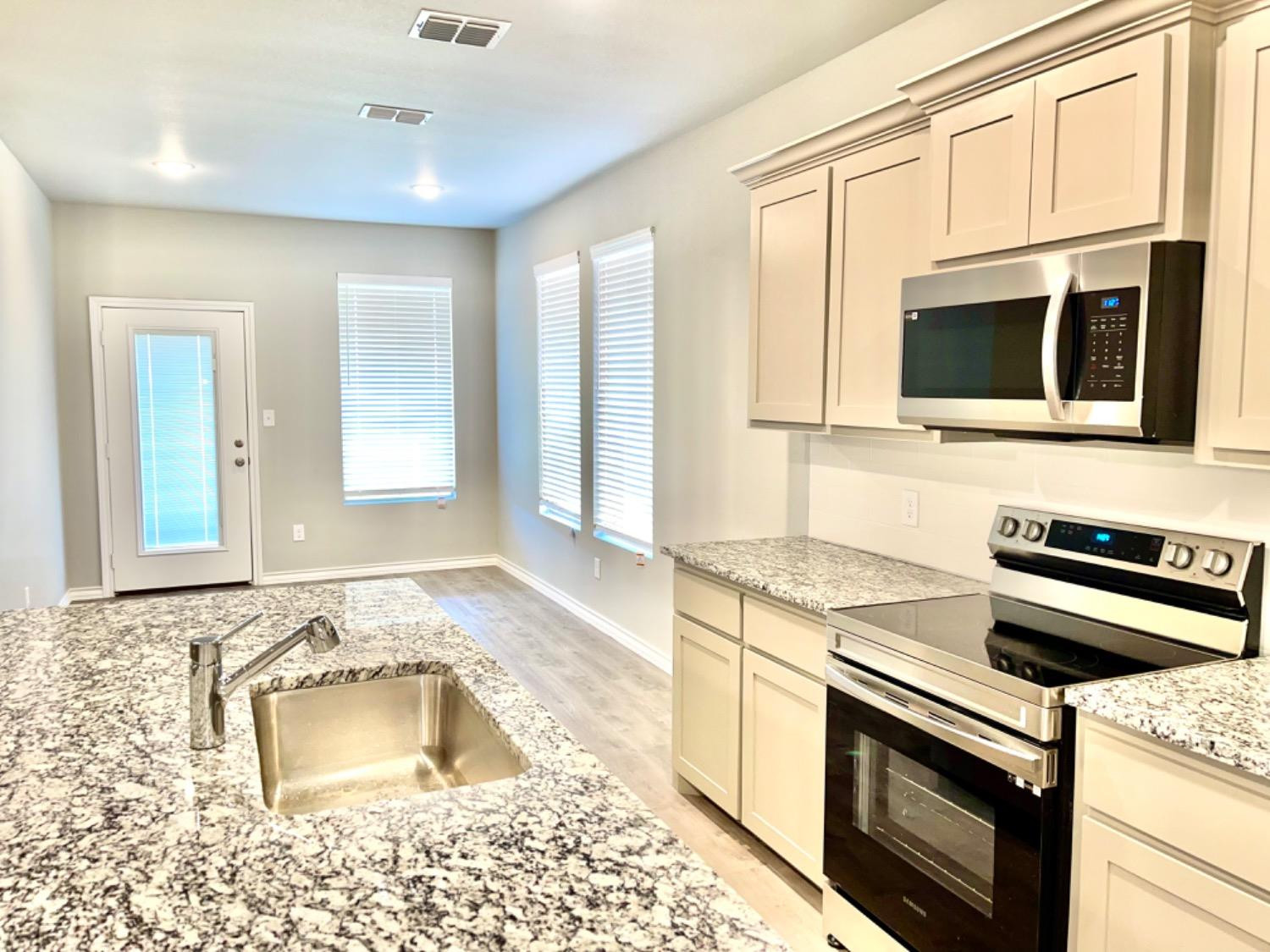 7729 96th Street Lubbock, TX 79424 - Photo 7 of 35 a kitchen with granite countertop a stove sink and microwave