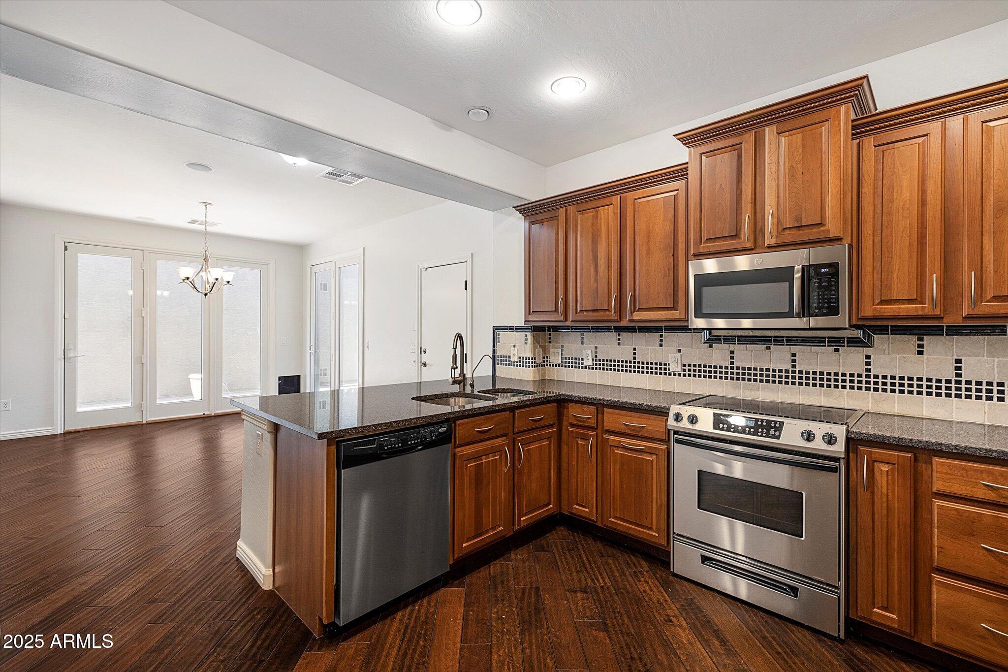 970 South Henry Lane Gilbert, AZ 85296 - Photo 43 of 51 a kitchen with stainless steel appliances granite countertop wooden cabinets a stove a sink and dishwasher with wooden floor