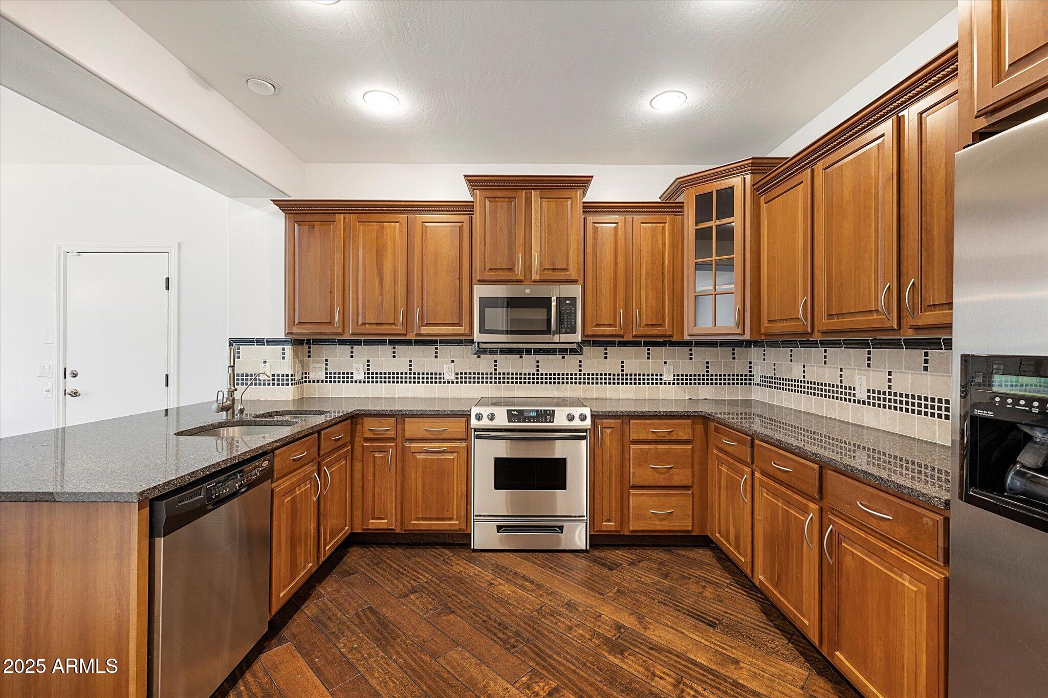 970 South Henry Lane Gilbert, AZ 85296 - Photo 8 of 51 a kitchen with stainless steel appliances granite countertop a stove top oven a sink dishwasher and a refrigerator with wooden cabinets
