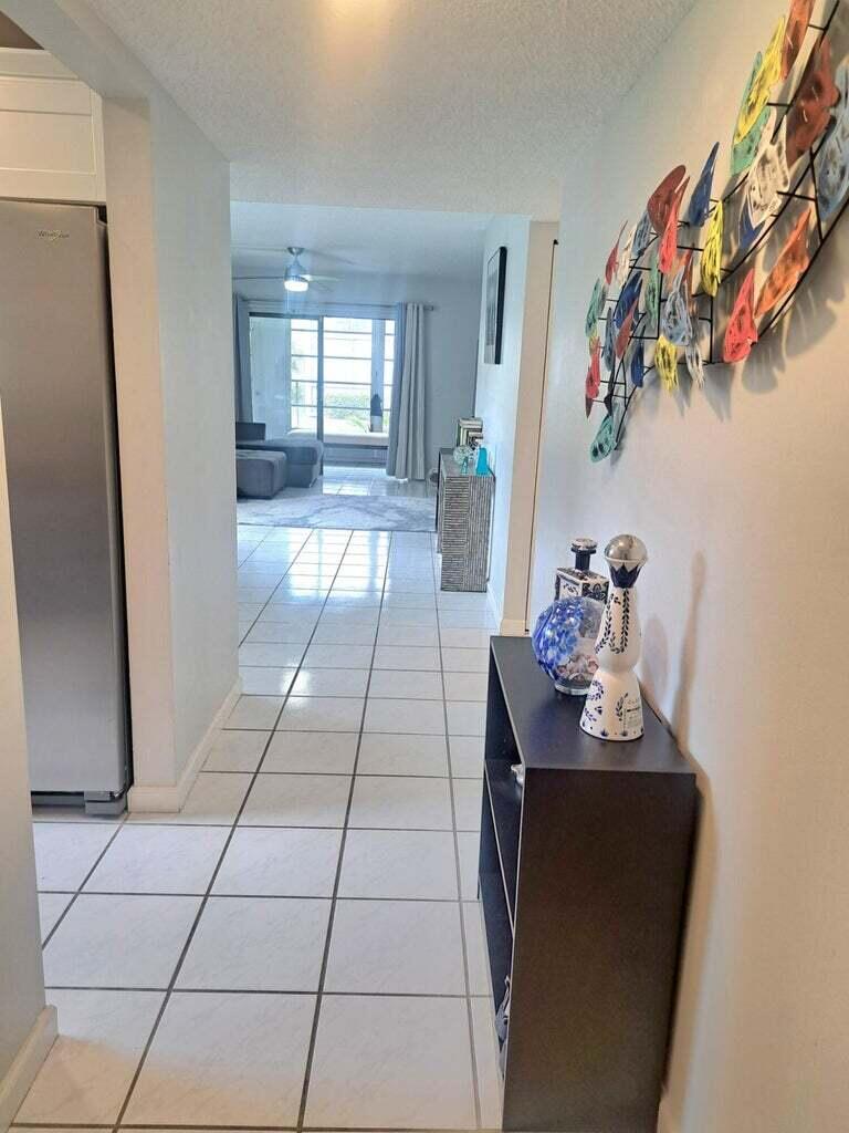 1700 Dover Road, Unit 113A Delray Beach, FL 33445 - Photo 11 of 13 a hallway with a dining table and a mirror