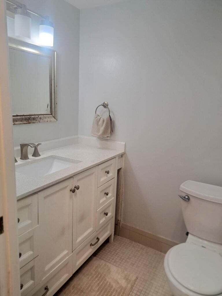 1700 Dover Road, Unit 113A Delray Beach, FL 33445 - Photo 8 of 13 a bathroom with a toilet sink and mirror