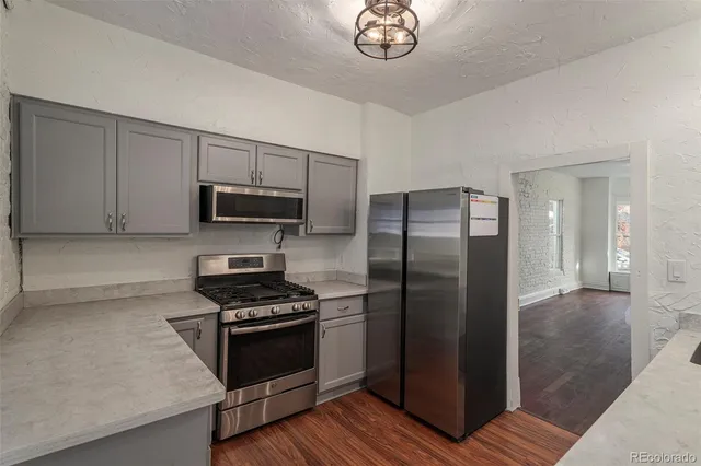 a kitchen with granite countertop a refrigerator and a stove top oven