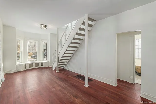 a view of an empty room with wooden floor and stairs
