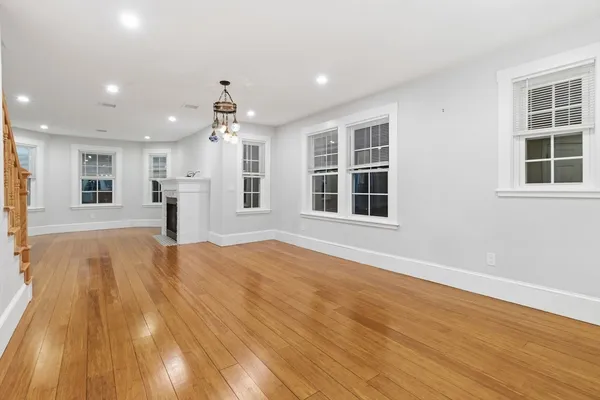 a view of an empty room with a window and wooden floor