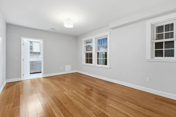 a view of an empty room with wooden floor and windows