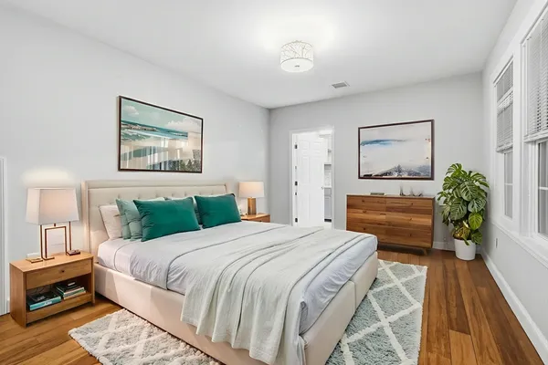a bedroom with a bed a dresser and potted plants
