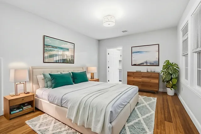 a bedroom with a bed a dresser and potted plants