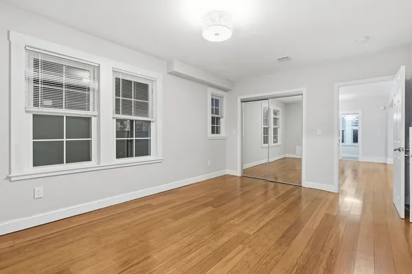 a view of empty room with wooden floor and windows