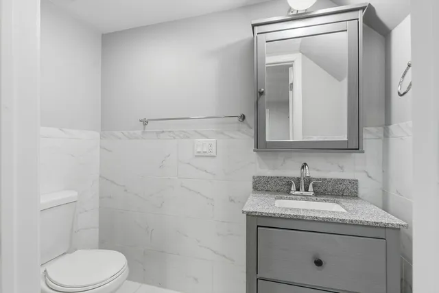 a bathroom with a granite countertop sink toilet and mirror