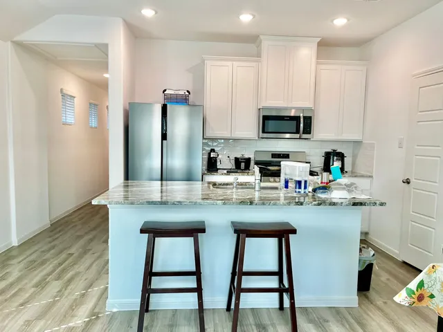 a kitchen with stainless steel appliances granite countertop a stove a sink a microwave a refrigerator and cabinets