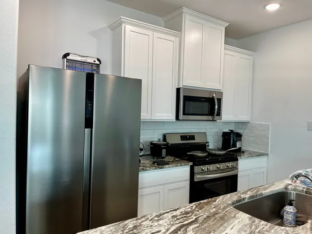 a kitchen with stainless steel appliances granite countertop a refrigerator and a stove top oven