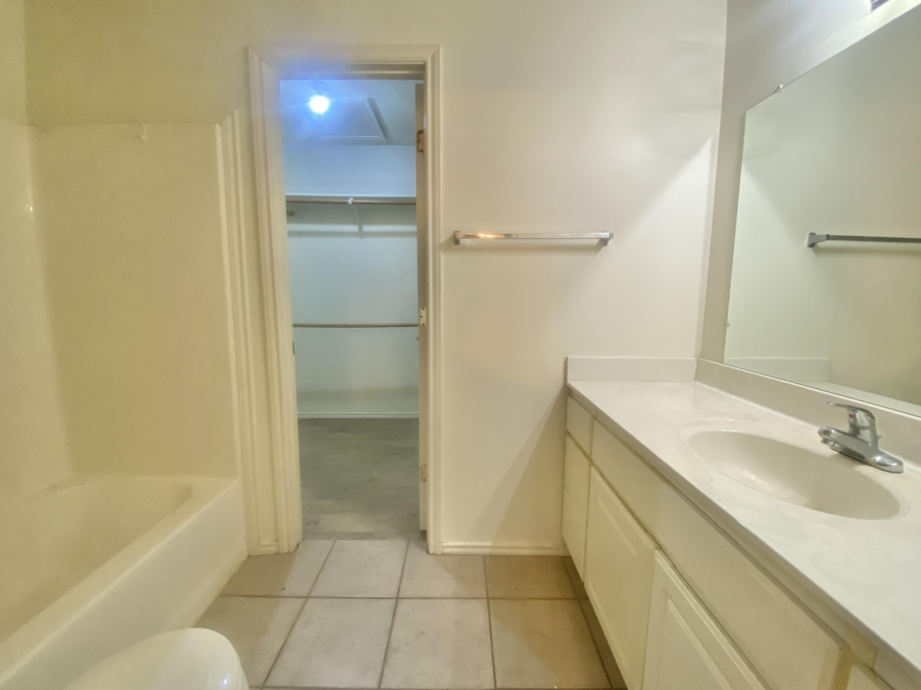 6319 7th Street Lubbock, TX 79416 - Photo 11 of 14 a bathroom with a granite countertop sink a toilet and shower