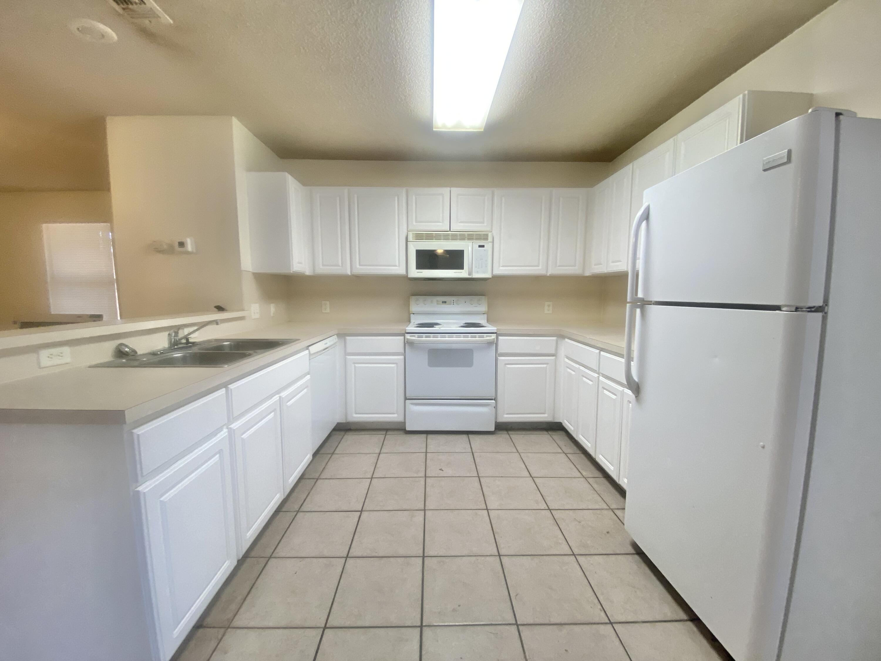6319 7th Street Lubbock, TX 79416 - Photo 5 of 14 a kitchen with a sink a refrigerator and a stove top oven