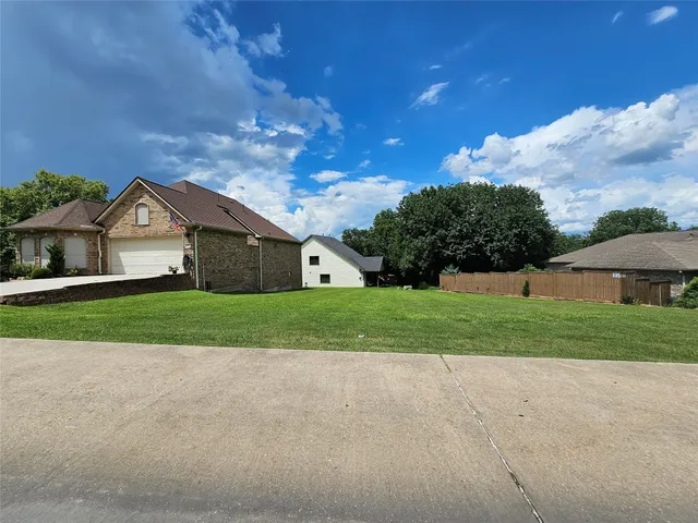 a view of house with a big yard and large trees