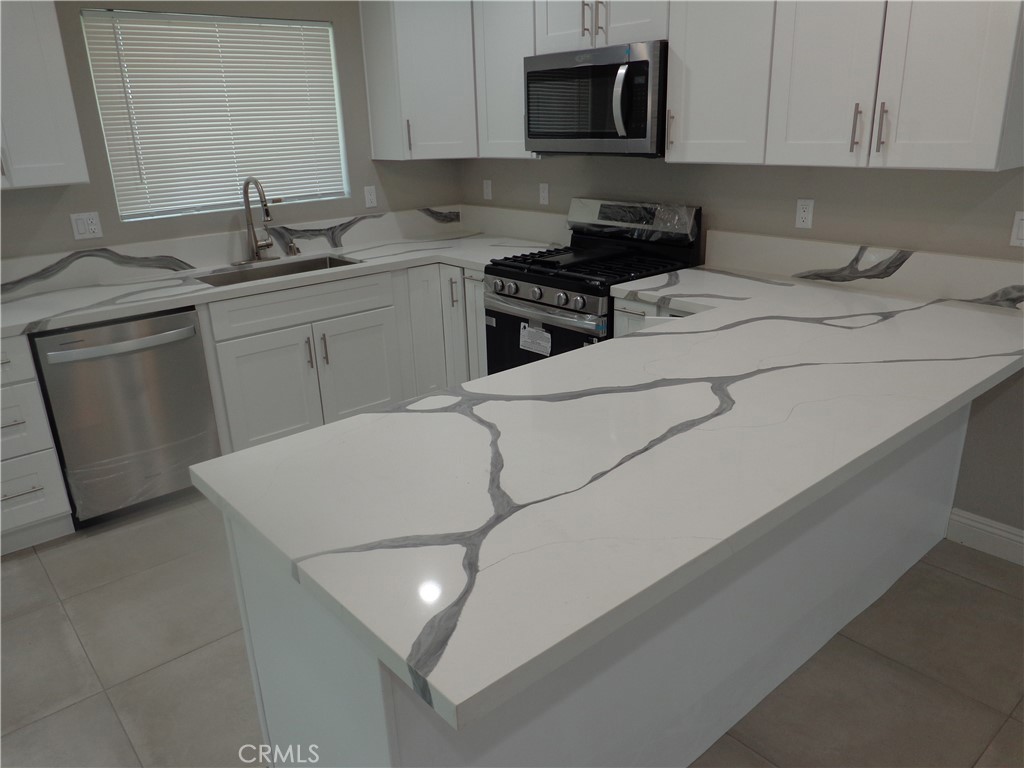 12744 Running Deer Road Apple Valley, CA 92308 - Photo 11 of 30 a kitchen with stainless steel appliances a sink dishwasher stove refrigerator and microwave