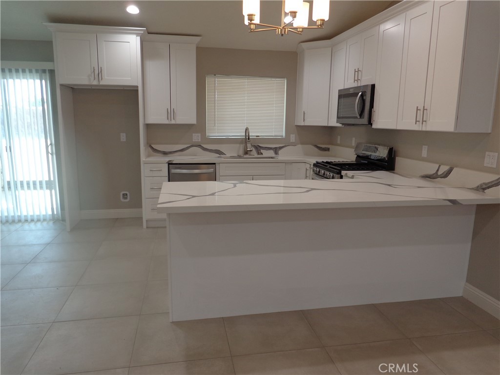 12744 Running Deer Road Apple Valley, CA 92308 - Photo 6 of 30 a kitchen with stainless steel appliances granite countertop a refrigerator a stove a sink and white cabinets