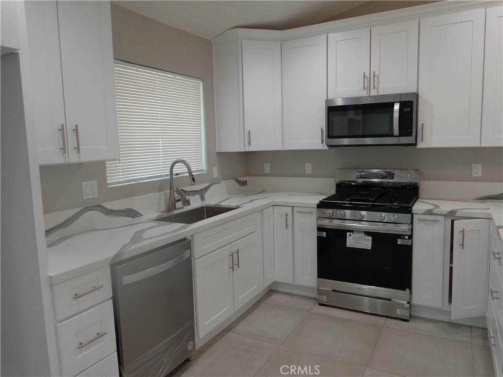 12744 Running Deer Road Apple Valley, CA 92308 - Photo 7 of 30 a kitchen with white cabinets and stainless steel appliances