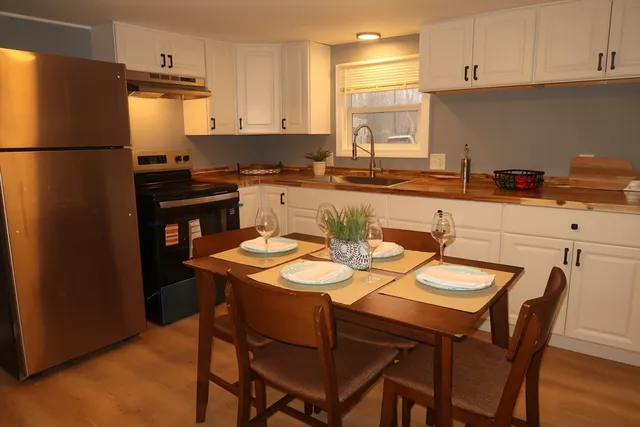 a kitchen with stainless steel appliances granite countertop a dining table chairs refrigerator and sink