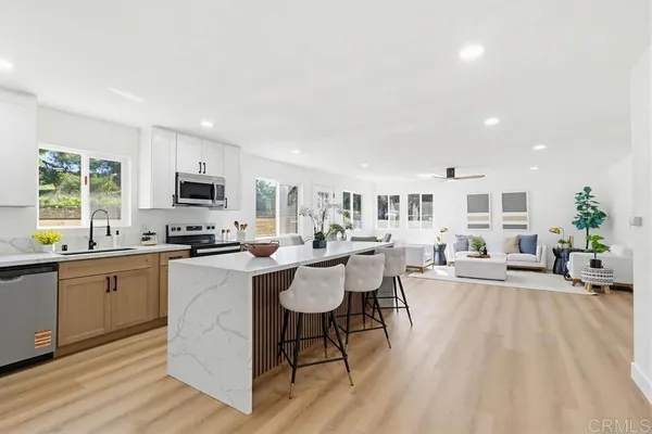 a living room with furniture a dining table wooden floor and a sink